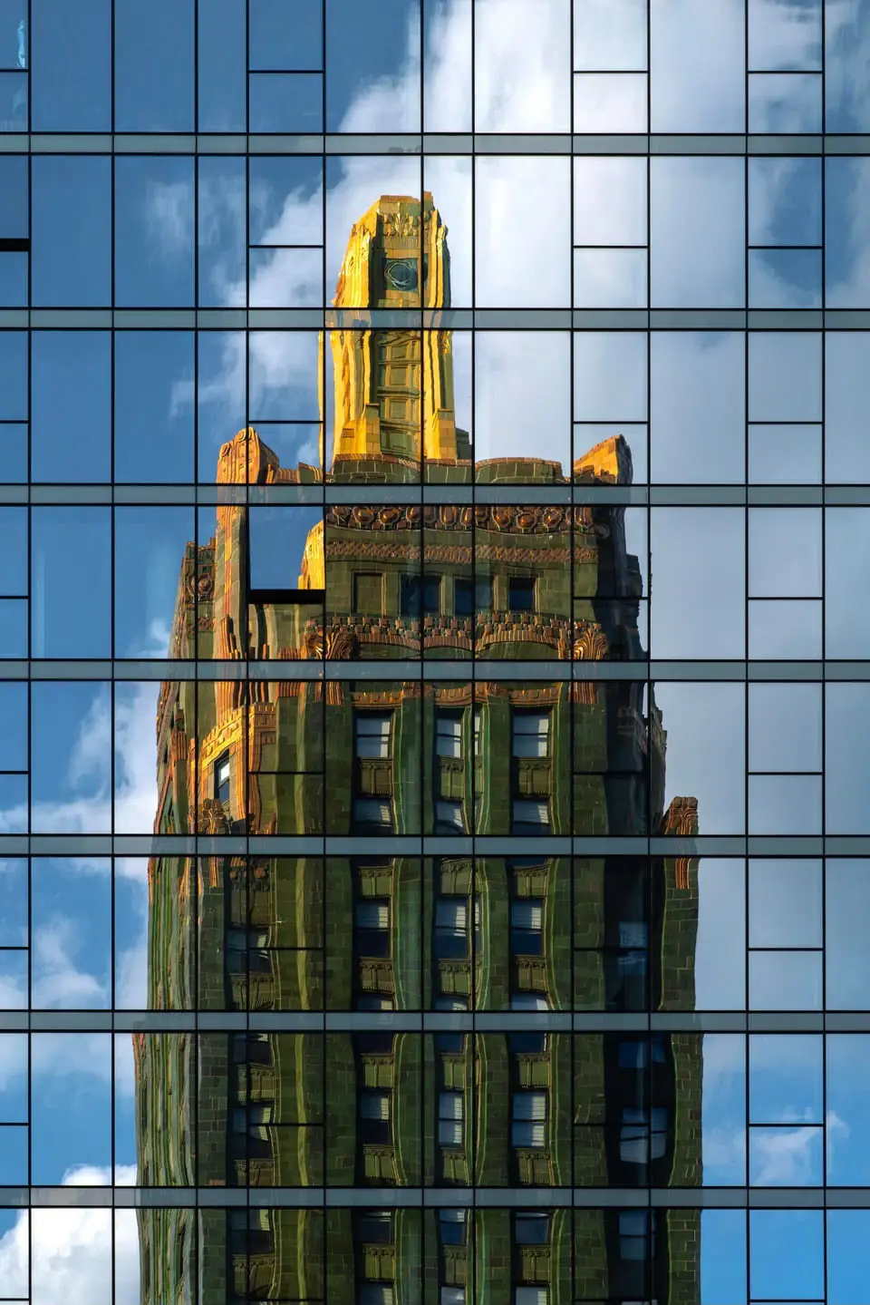The gold-topped Carbide and Carbon Building reflected in a glass tower