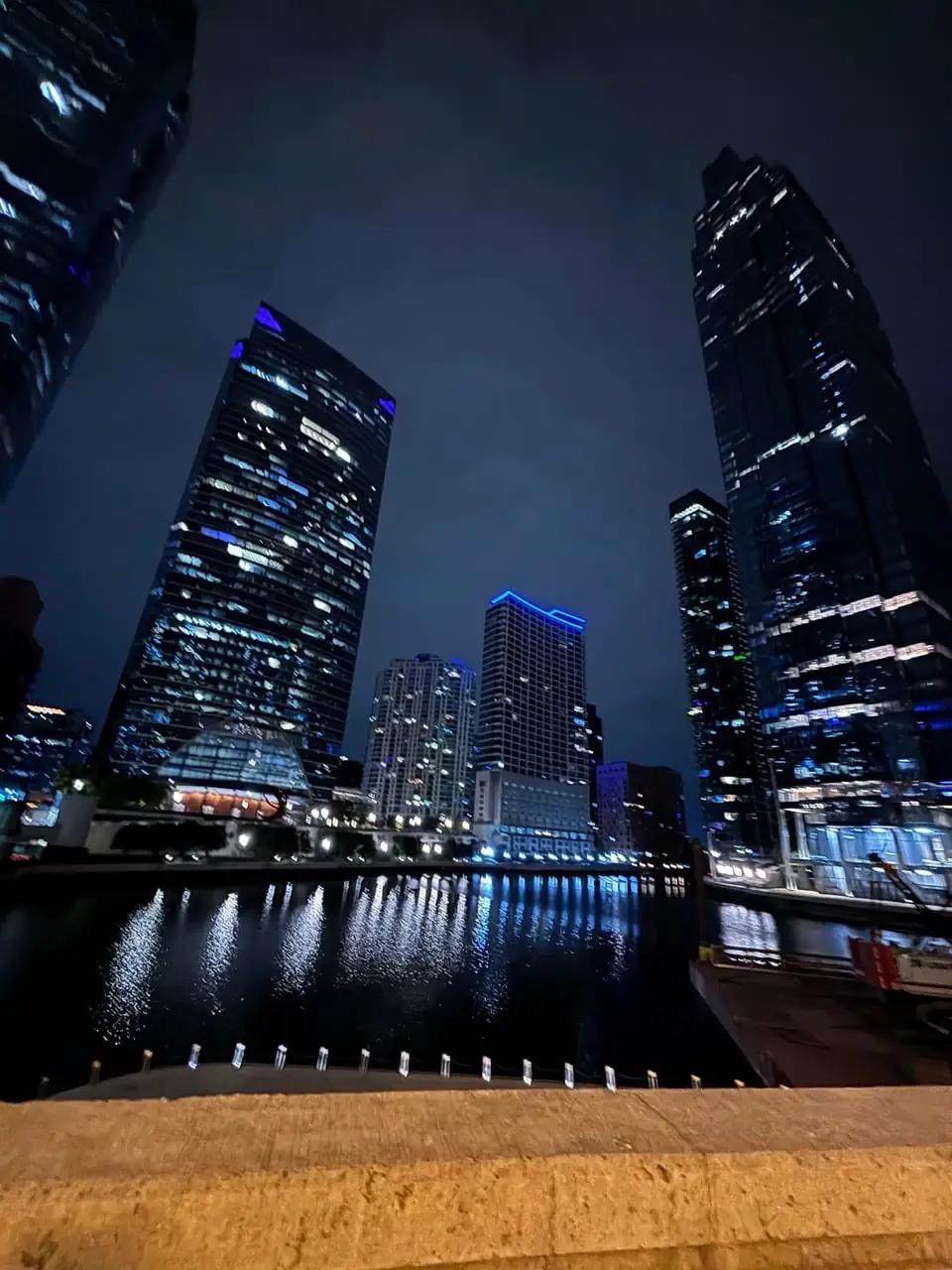 Blue-lit glass towers along the Chicago River at night