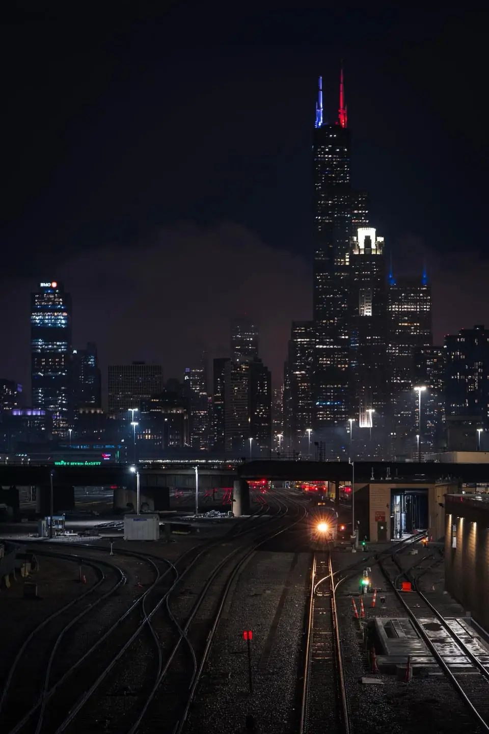 The Chicago skyline and Willis Tower at night above a rail yard