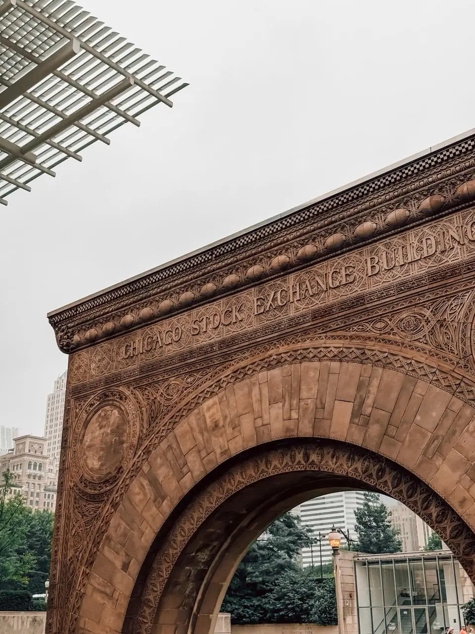 The carved Chicago Stock Exchange arch with trees behind it