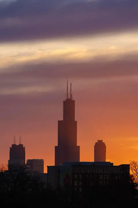 Willis Tower in silhouette against an orange Chicago sunset