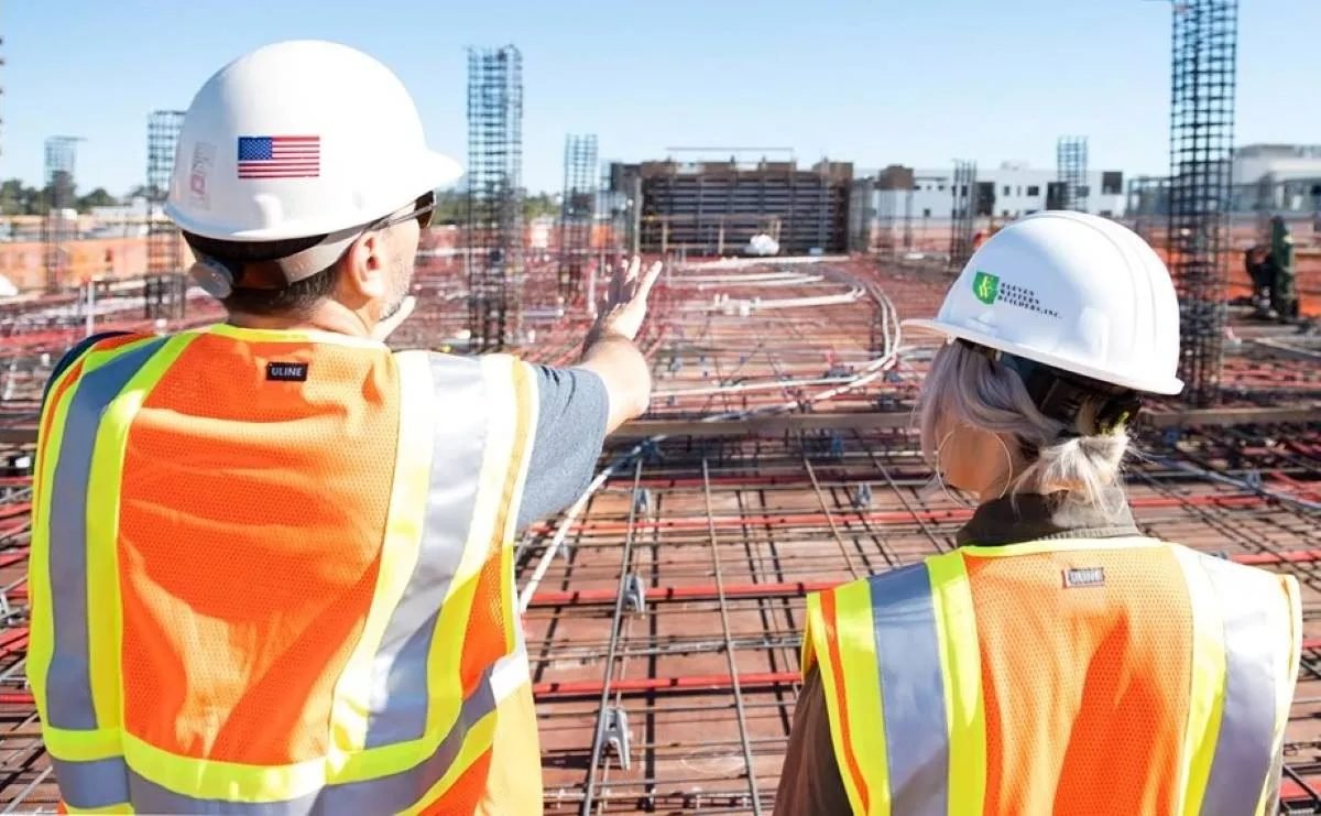 Two contractors in hard hats and safety vests reviewing a rebar foundation on a jobsite