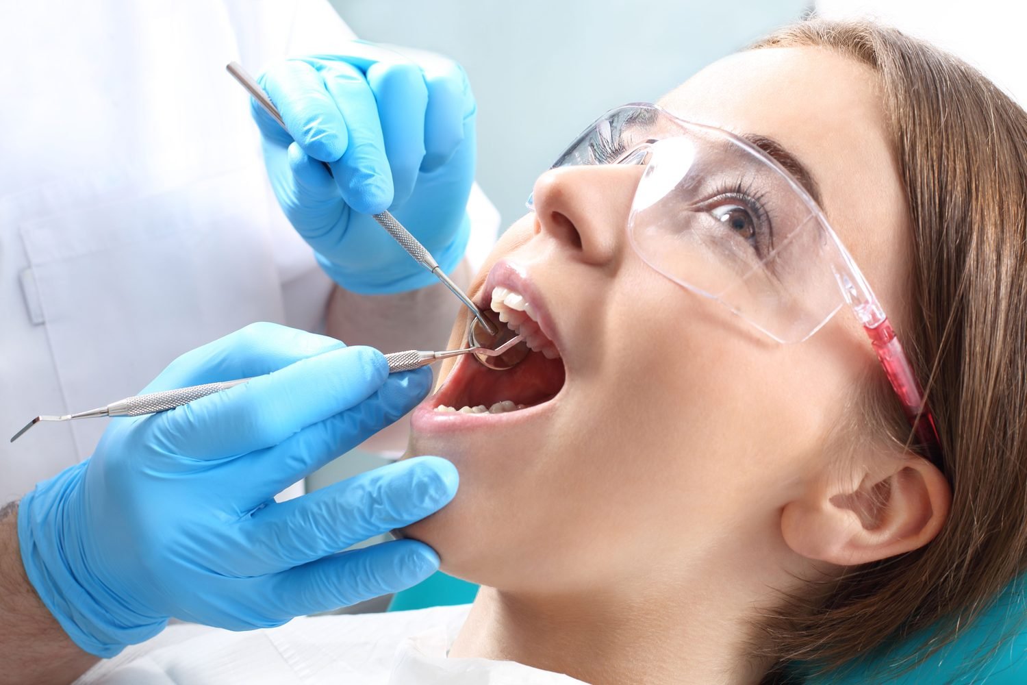 Dental hygienist examining a patient wearing protective eyewear