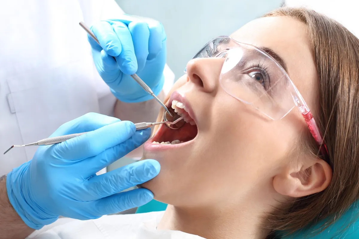 Dental hygienist examining a patient wearing protective eyewear
