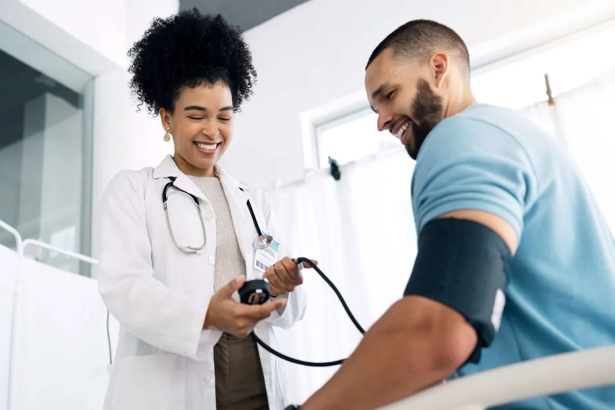 Doctor checking a smiling patient's blood pressure in an exam room