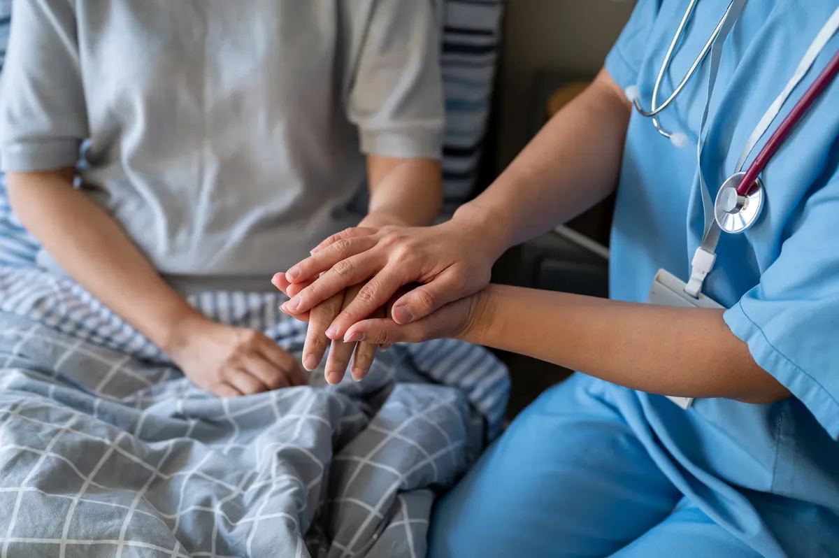 Nurse holding a patient's hand at the bedside