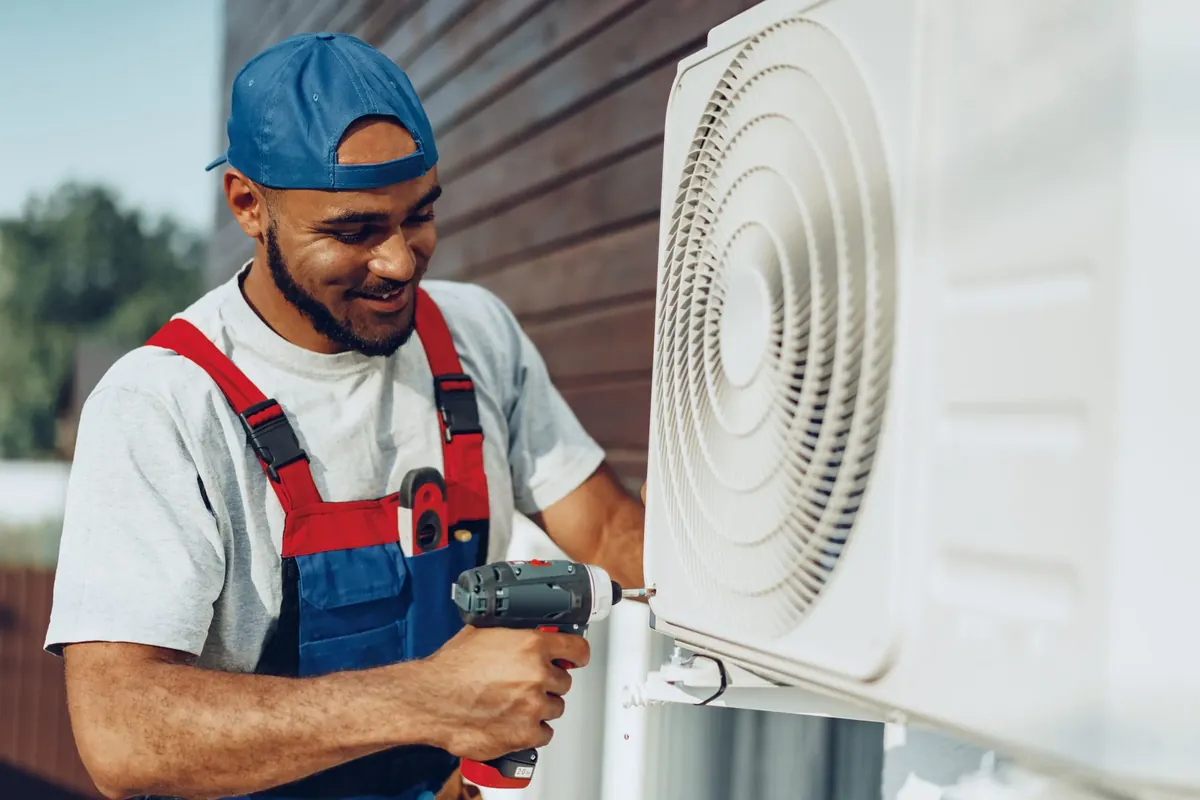 Technician installing an outdoor air conditioning unit with a power drill