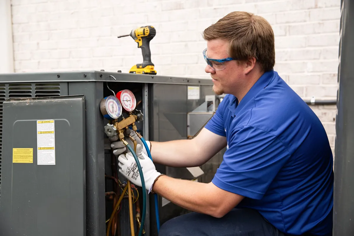 HVAC technician checking refrigerant pressure on an outdoor air conditioning unit