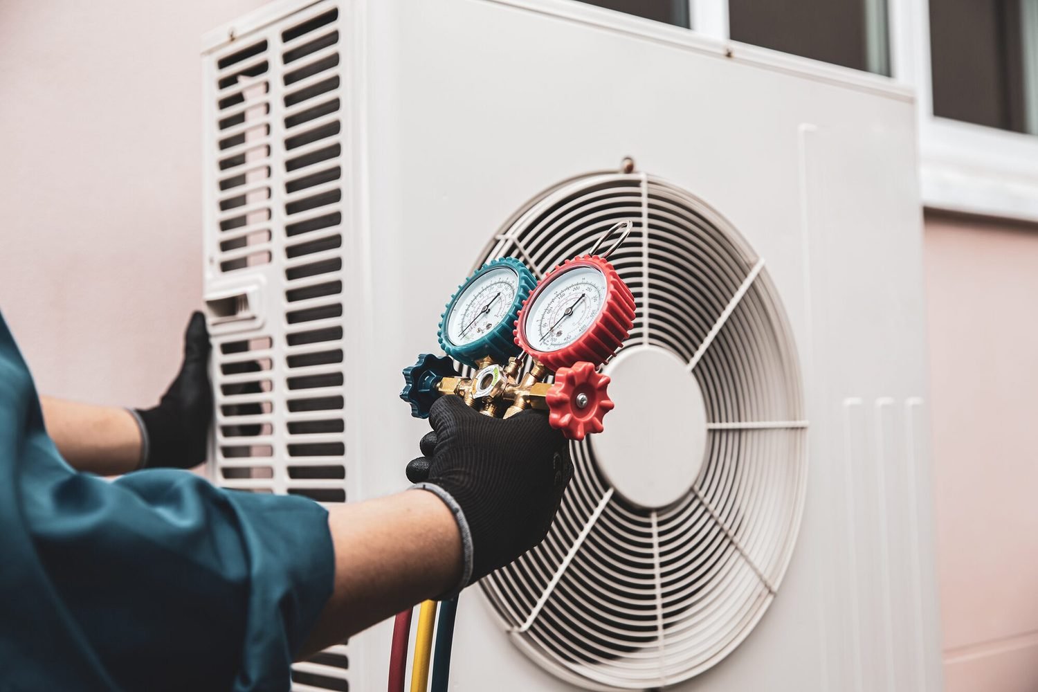 Technician using manifold gauges to service an outdoor air conditioning unit