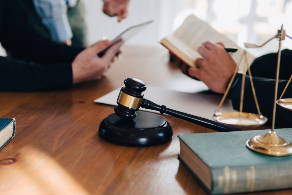 Two attorneys reviewing a case file with a gavel and scales of justice on the table