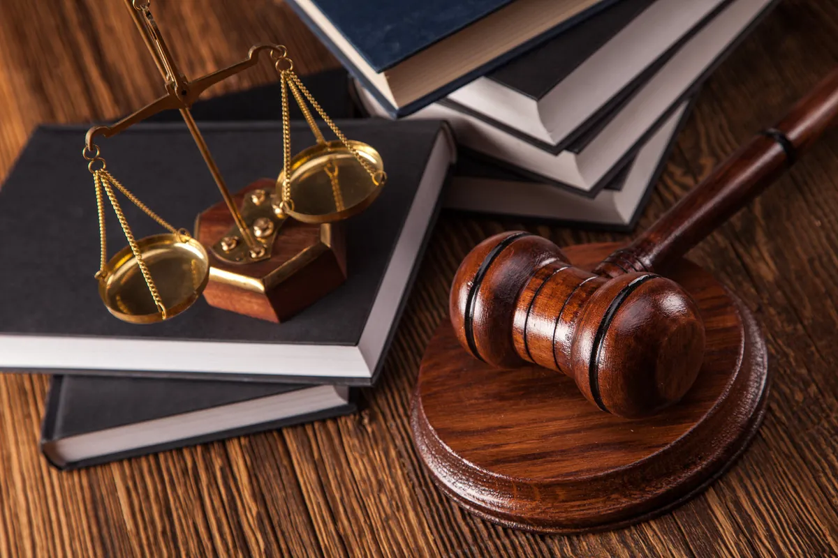 Wooden gavel, brass scales of justice, and law books on a desk